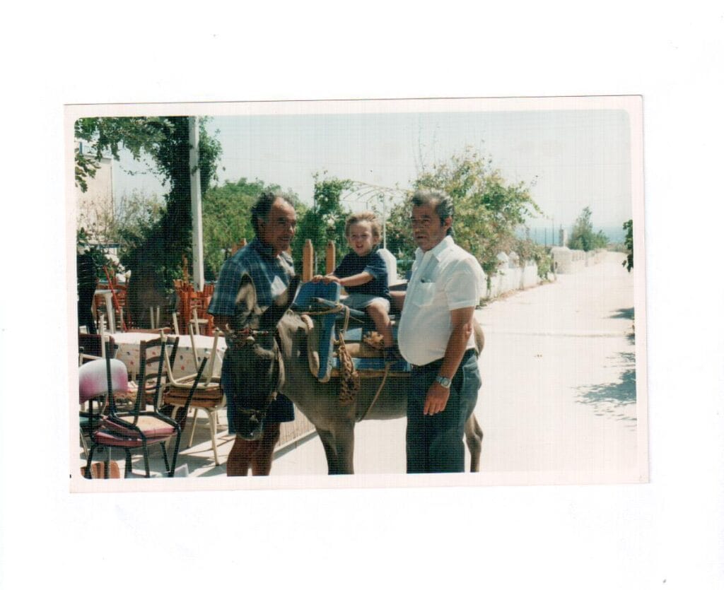 Child riding a donkey with grandparents in Ambelas, Paros island