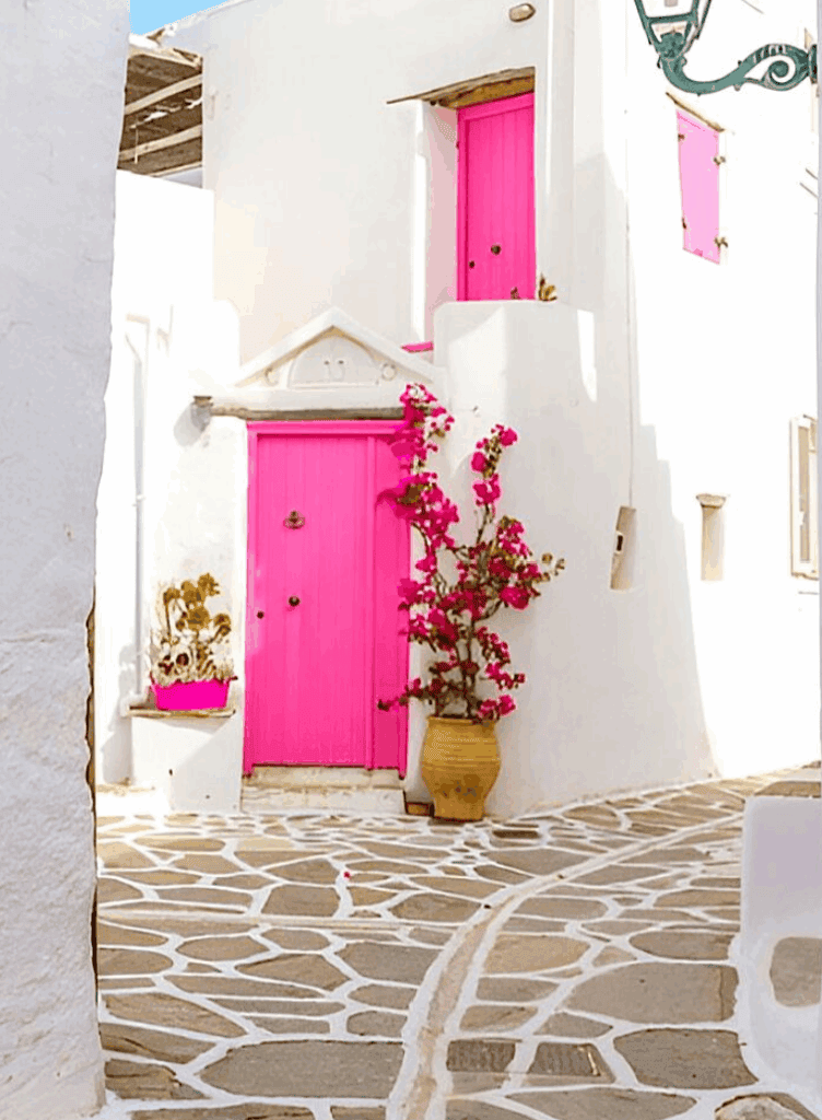 Traditional pink door and potted plant outside a Greek island house
