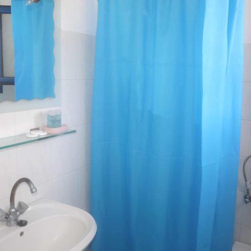 Bathroom with blue shower curtain in Aegean Grand Apartment Ambelas Paros